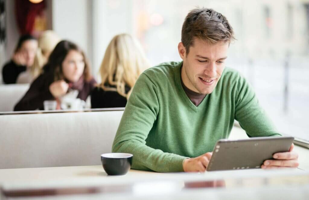 Young man / student using tablet computer in cafe